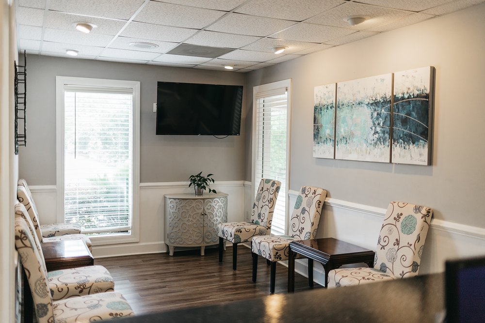 Modern dental office waiting room with chairs, TV, and decor at Cross County Dentistry in North Charleston, SC