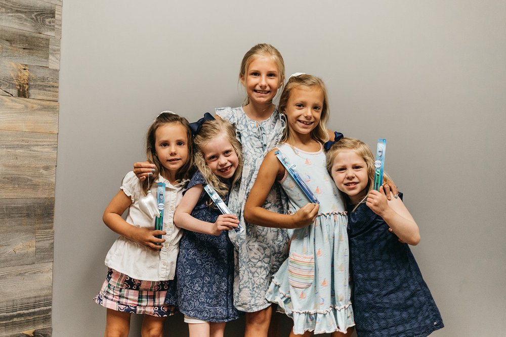 Group of smiling children holding toothbrushes at Cross County Dentistry in North Charleston, SC